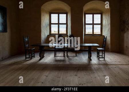 Interni del Castello di Bauska - stanza con tavolo in legno e quattro sedie scolpite, vetrate e due candele sul tavolo Foto Stock