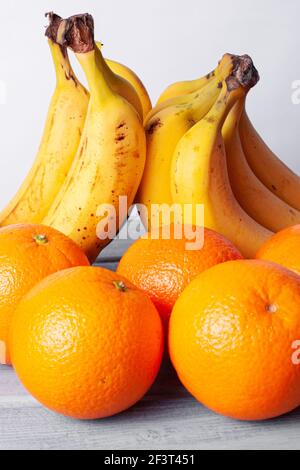 Vista delle arance e delle banane allineate su un grigio tabella su sfondo bianco Foto Stock