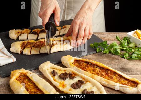 Il kasarli sucuklu pide e il kimali pide sono tradizionali piatti turchi simili alla pizza con condimenti di carne e formaggio. Vengono serviti con limone An Foto Stock