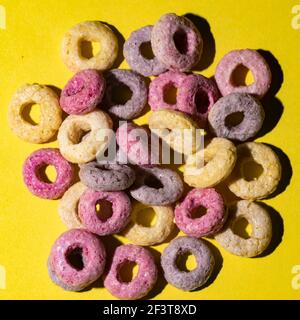 Cereali colorati su sfondo giallo. Una colazione colorata. Foto Stock