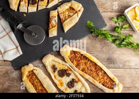 Il kasarli sucuklu pide e il kimali pide sono tradizionali piatti turchi simili alla pizza con condimenti di carne e formaggio. Vengono serviti con limone An Foto Stock