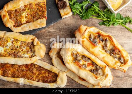 Il kasarli sucuklu pide e il kimali pide sono tradizionali piatti turchi simili alla pizza con condimenti di carne e formaggio. Vengono serviti con limone An Foto Stock