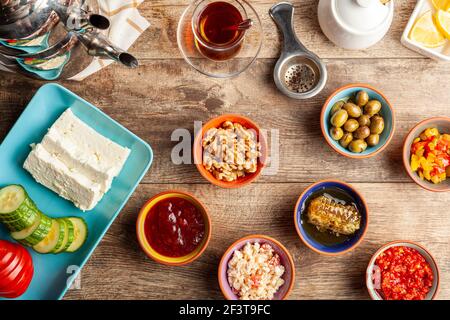 Sana colazione turca, con pomodoro a fette, cetriolo e formaggio feta bianco, piccole ciotole di marmellata di fragole, olive, miele, pasta di pepe. Il tè è servito Foto Stock