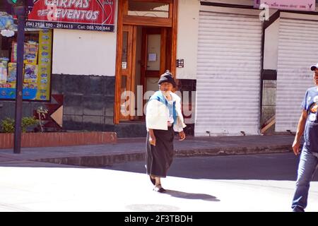 Donna indigena che attraversa la strada a Cotacachi, Ecuador Foto Stock