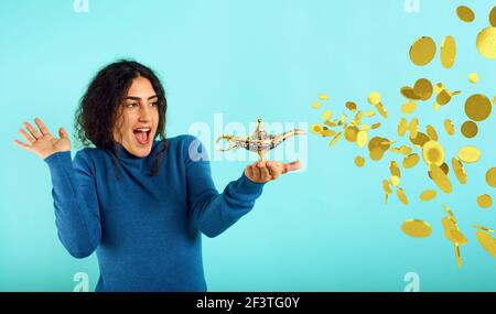 Donna è felice becaouse che fonda la lampada di aladdin e ha chiesto i soldi. Sfondo ciano Foto Stock