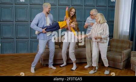 Familiari di generazioni diverse che si divertono ascoltando musica, ballando pazzi in camera a casa Foto Stock
