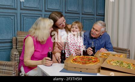 Felice famiglia multigenerazionale con pranzo a casa, mangiare cibo pizza, brindisi insieme Foto Stock