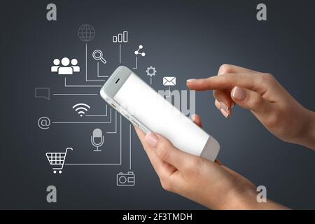 Mani femminili con telefono cellulare su sfondo scuro. Concetto di marketing digitale Foto Stock