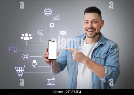Bell'uomo con telefono cellulare su sfondo grigio. Concetto di marketing digitale Foto Stock