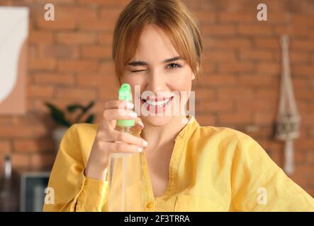 Giovane donna con deodorante in cucina Foto Stock