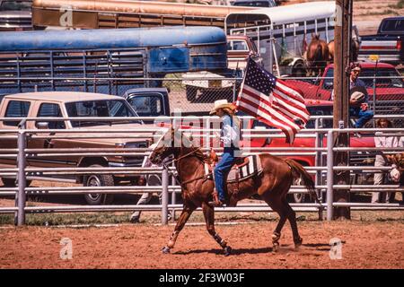 Una cowgirl a cavallo presenta la bandiera americana all'inizio di un rodeo di una piccola città nel New Mexico. Foto Stock