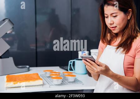 Donna proprietario panificio negozio utilizzando smartphone per la sua attività Foto Stock