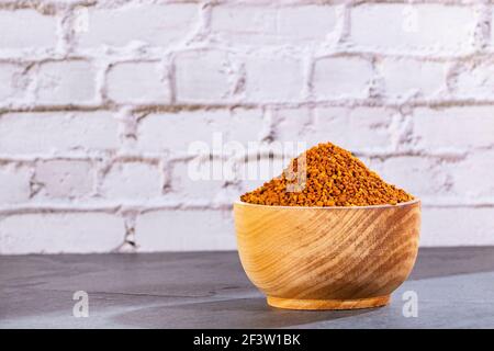 Grani organici del polline dell'ape nella ciotola di legno Foto Stock