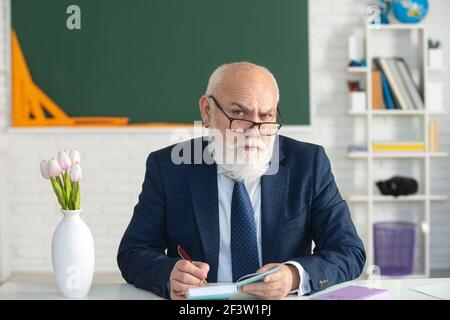 Professore tenendo un libro e indicando con un bastone di legno isolato su sfondo bianco. Conoscenza e concetto di istruzione tradizionale. Foto Stock