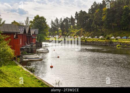 Case sul lungomare con attracchi per imbarcazioni fiancheggiano il fiume Porvoonjoki in una tranquilla giornata estiva nel borgo medievale di Porvoo, Finlandia. Foto Stock