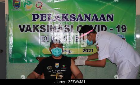 Medico che tiene la siringa e che usa il cotone prima di fare l'iniezione al paziente in maschera medica Covid-19 o vaccino del coronavirus, Batang, Indonesia, marzo 15, Foto Stock