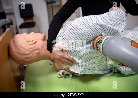 Oldenburg, Germania. 02 marzo 2021. Le armi robotizzate aiutano Anna Brinkmann, assistente di ricerca, a muovere una bambola durante un allestimento sperimentale all'Università Carl von Ossietzky. Finora, non vi è stato alcun sostegno da parte dei robot nel settore della cura. Un team di ricercatori di Brema e bassa Sassonia vuole cambiare questo e vede grandi opportunità nel campo delle armi robotiche. Credit: Sina Schuldt/dpa/Alamy Live News Foto Stock