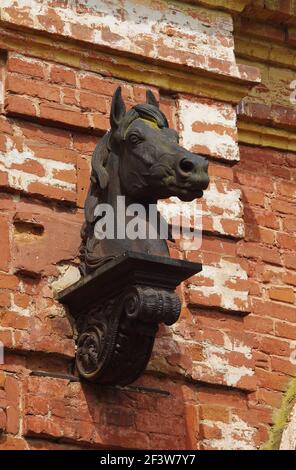 Scultura della testa di un cavallo sulla parete in mattoni di un allevamento di prigionieri abbandonato del 19 ° secolo (Oblast Pskov, Russia) Foto Stock