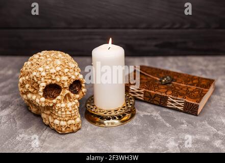 Ancora vita con cranio spaventoso, libro antico e candele nere. Cranio Foto Stock