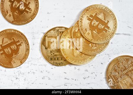 Vista dall'alto, btc commemorativa d'oro - criptovaluta bitcoin - monete sparse su tavola di pietra bianca, dettaglio closeup Foto Stock