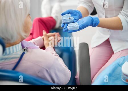 Adulto che dà una scelta di due calchi dentali blu Foto Stock
