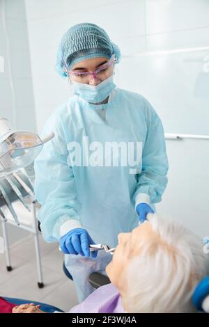 Stomatologo esperto afferra un dente con le pinze di estrazione Foto Stock