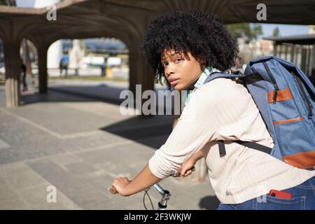 Donna Latina in bicicletta in città. Donna afroamericana che usa il trasporto verde . Foto di alta qualità Foto Stock
