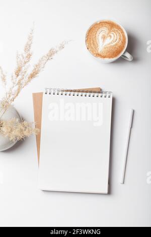 scrivania da lavoro con notebook, matita, caffè e pampas erba in vaso. Disposizione piatta, vista dall'alto, business, lavoro, concetto mockup. Spazio copia. Foto Stock