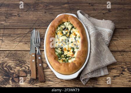 Torta aperta al formaggio con bietole in stile Adjara sul tavolo di legno, vista dall'alto. Deliziosi piatti fatti in casa Foto Stock