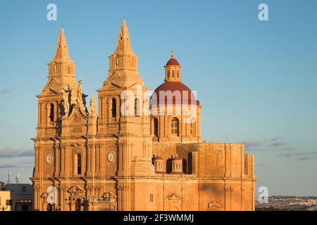 Chiesa parrocchiale illuminata dal sole del mattino in una calda giornata di autunno a Mellieha, Malta. Foto Stock