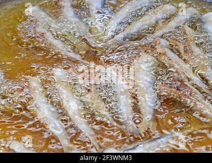 Acciughe frittura in una padella. Preparazione delle acciughe fritte Foto Stock