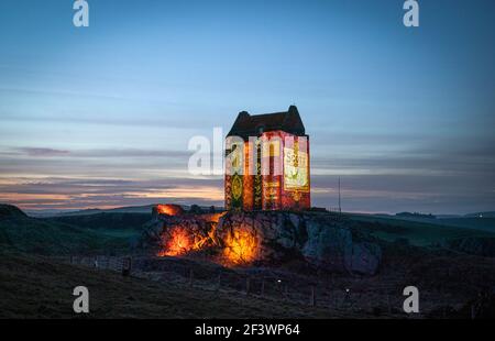 La Torre di Smailholm, nei pressi di Kelso, ai confini scozzesi, è illuminata dalla prima mondiale di un nuovissimo cortometraggio "Young Scott", creato dal video artista Andy McGregor, per lanciare le celebrazioni internazionali per il 250° anniversario della vita e delle opere di Sir Walter Scott. Una trasmissione online dell'evento presenterà lo spettacolo di luci della Torre di Smailholm a un pubblico mondiale a partire dalle 18:00 (GMT) di sabato 20 marzo, Giornata mondiale della narrazione. Data immagine: Mercoledì 17 marzo 2021. Foto Stock