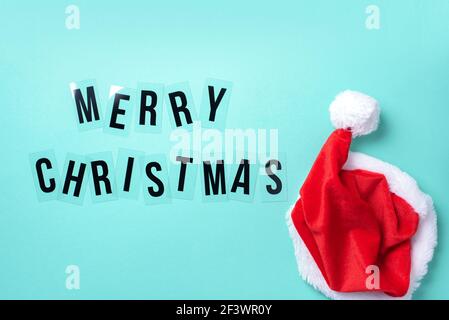 Cappello rosso brillante di Babbo Natale su sfondo blu. Vista dall'alto. Spazio di copia. Buon Natale concetto. Banner. Tempo di avvento. Composizione del nuovo anno. Decorazione Foto Stock