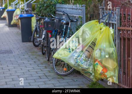 Sacchetti gialli per rifiuti di plastica, appesi su una recinzione da giardino, Germania Foto Stock