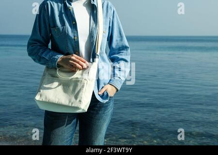 Donna con elegante borsa ecologica contro il mare Foto Stock