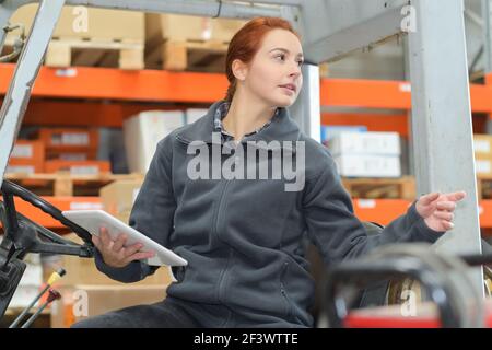 donna che guida un carrello elevatore a forche in magazzino Foto Stock