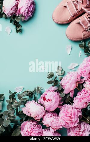 Sneakers rosa, peonie rosa pastello, fiori di eucalipto su sfondo blu pastello. Disposizione piatta, vista dall'alto. Spazio di copia. Composizione floreale. Matrimonio Foto Stock