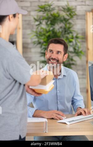 uomo d'affari che riceve la consegna del pranzo nel suo ufficio Foto Stock