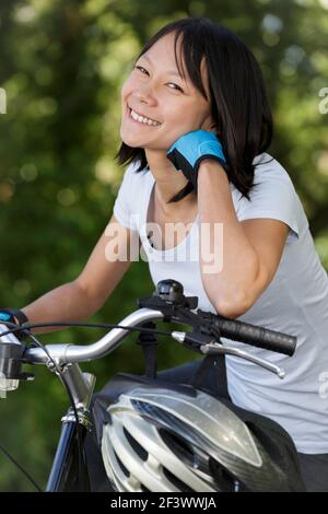 donna felice in bicicletta in foresta che si riposa Foto Stock