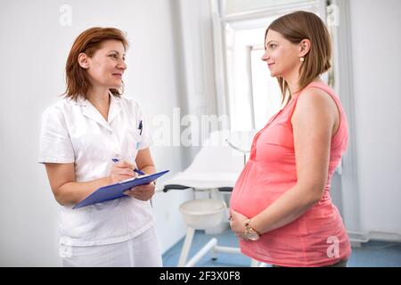 Infermiera che pesa donna incinta in ambulanze Foto Stock