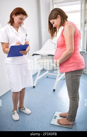 Infermiera che pesa donna incinta in ambulanze Foto Stock