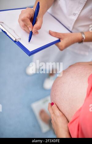 Infermiera che pesa donna incinta in ambulanze Foto Stock