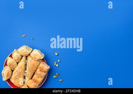 Dolce turco baklava con pistacchi su sfondo blu. Vista dall'alto. Spazio di copia. Set di dolci orientali tradizionali assortiti. Dolci arabi Foto Stock