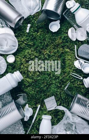 Riutilizzare rifiuti, riciclare, senza plastica. Imballaggio alimentare in plastica, rifiuti su sfondo muschio verde dopo pic-nic in foresta. Vista dall'alto. Spazio di copia. Riciclaggio Foto Stock