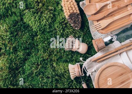 Concetto di zero sprechi. Borsa di cotone, posate di bambù, vasetto di vetro, spazzolini da cucina di bambù, cannucce su fondo muschio verde. Vista dall'alto. Spazio di copia. Sostenibile Foto Stock