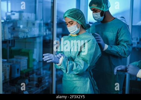 Medico e infermiere che si preparano a lavorare in ospedale per l'intervento chirurgico Operazione durante l'epidemia di coronavirus - Focus sul viso della donna Foto Stock