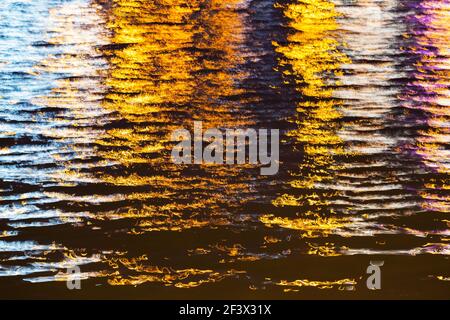 luce colorata sulla superficie del fiume di notte in città Foto Stock