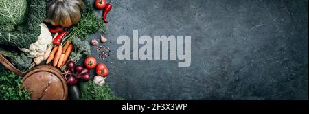 Pentola di rame, erbe, cipolla viola, zucca, pomodoro, broccoli, pepe, cavolo, carota, prezzemolo, calafiore, zucchine su sfondo scuro. Vista dall'alto. Copia Foto Stock