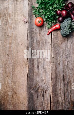 Pentola di rame, erbe, cipolla viola, zucca, pomodoro, broccoli, pepe, cavolo, carota, prezzemolo, calafiore, zucchine su fondo ligneo. Vista dall'alto. Copia Foto Stock