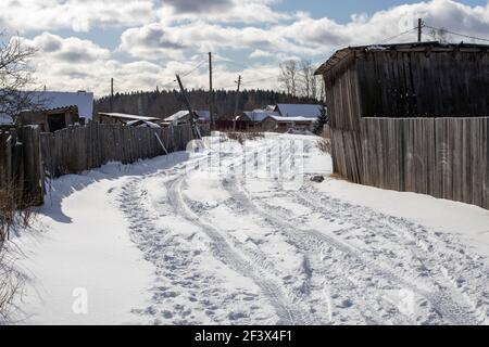 strada nel villaggio coperta di neve con tracce di pneumatici auto. Foto di alta qualità Foto Stock
